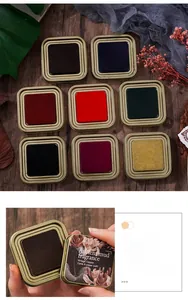Detail of vintage square metal tin ink pads with elegant floral engraving on wood background