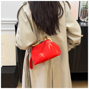 Detail of red silk embroidery bag with natural bamboo handle and fringe on a trench coat