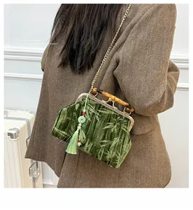 Detailed view of velvet handbag featuring bamboo handle and green silk tassel decoration