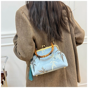 Detail of bamboo handle and leaf embroidery on a light blue satin qipao handbag
