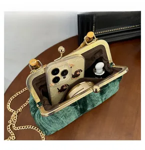 Detail view of green velvet handbag with bamboo handle, gold clasp and internal capacity