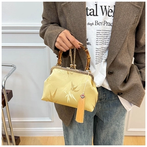Detail of yellow silk handbag with bamboo handle, gold embroidery and fringe tassel