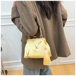 Detailed view of the yellow silk bag with bamboo pattern and elegant gold chain strap