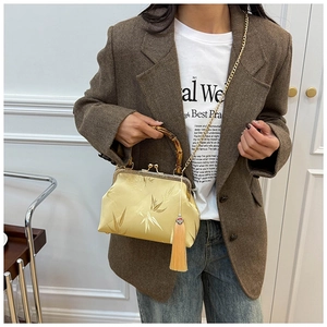 Detail of elegant yellow brocade cheongsam bag with bamboo handle and golden tassel