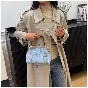 Detail of light blue jacquard handbag with bamboo handle and jade tassel accessory