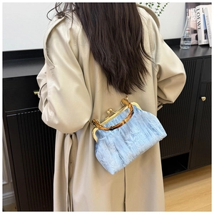 Detail of light blue embroidered handbag with bamboo handle and golden metal frame