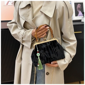 Detail of black velvet bag with bamboo handle, gold metal frame and green silk tassel