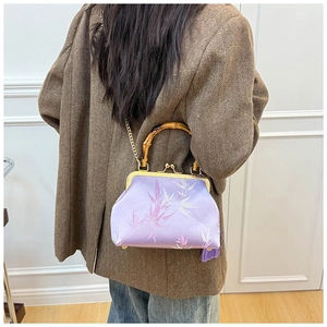 Detail of purple embroidery bag with bamboo handle and gold chain on a model