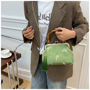 Detailed view of a green silk handbag with bamboo handle, leaf pattern and gold tassel