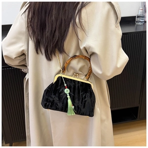 Close-up of velvet handbag featuring a natural bamboo handle and green tassel detail