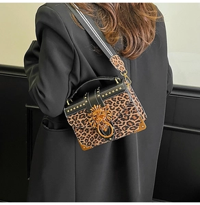 Detail of leopard print handbag with golden lion head metal buckle and rivet accents