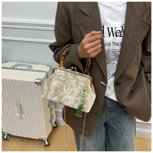 Retro velvet bag with bamboo handle and leaf embroidery worn by model over a suit