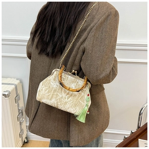 Detailed view of apricot velvet bag with bamboo handle, white embroidery and tassel
