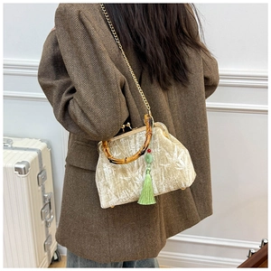 Detail of velvet bag featuring bamboo handle, gold chain strap, and green silk tassel
