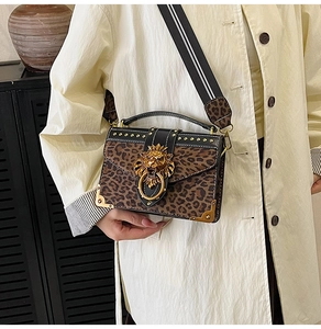 Detail of leopard print handbag featuring a gold lion head buckle and metal studs border