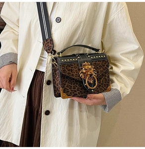 Detail of leopard print crossbody bag with gold lion head buckle and studded metal corners