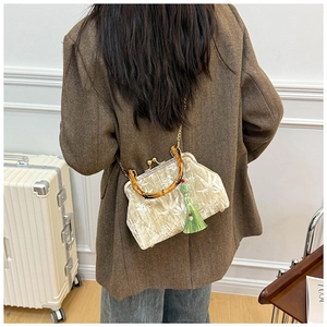 Close-up of khaki velvet bag with bamboo handle, leaf print, and silk tassel detail