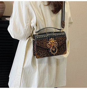 Close-up of leopard print handbag with golden lion head emblem and metal studs