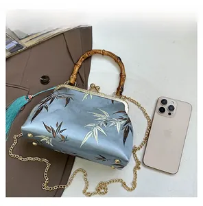 Detail view of blue silk cheongsam bag with bamboo handle, fringe and metal kiss lock