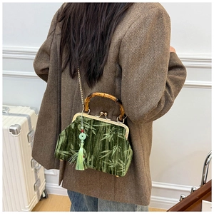 Close-up of dark green velvet bag with bamboo handle and elegant silk tassel detail