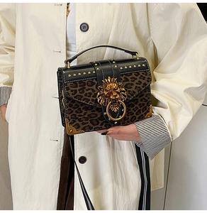 Close-up of leopard print handbag featuring a golden lion head clasp and metal rivets