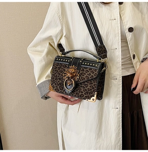 Close-up of leopard print handbag featuring a gold lion head buckle and studded leather trim