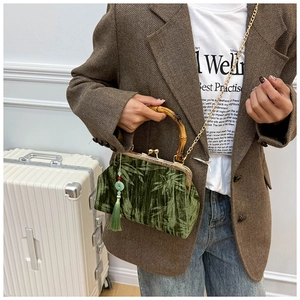 Detail of green velvet bag with bamboo handle and silk tassel on model in suit