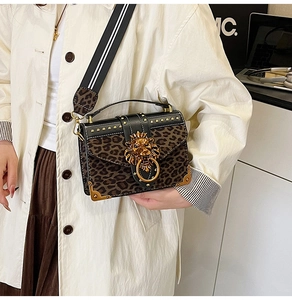 Detail of leopard print crossbody bag featuring golden lion head and studded edges
