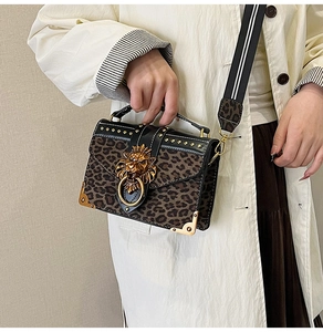 Detail of leopard print handbag with golden lion head buckle and studded leather edges