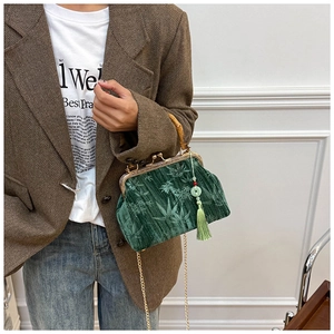 Detail of green velvet bag with bamboo handle, leaf texture, and jade tassel ornament