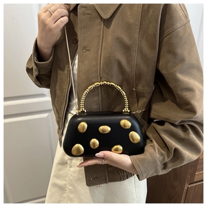 Detail der luxuriösen schwarzen Ledertasche mit goldenen Kieselakzenten und Bambusgriff