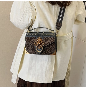 Detail of leopard print crossbody bag with golden lion head emblem and metal studs