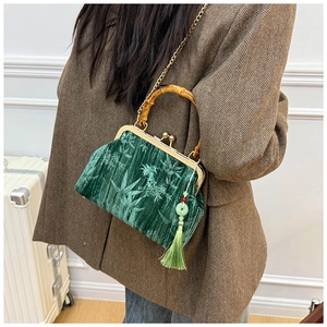 Detail of velvet bag featuring bamboo handle, green leaf pattern, and tassel charm