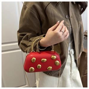 Detailsicht der roten matten Clutch mit goldenen Kieselsteinen und Perlenhandgriff