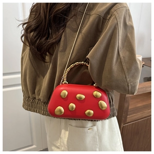 Detail der roten Luxushandtasche mit goldenen Kieselakzenten und Perlengriff