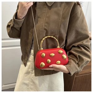 Details einer roten halbkreisförmigen Handtasche mit Nieten und goldenem Ringgriff