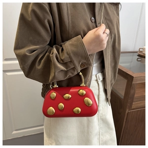 Detail der roten Abendtasche mit goldenen Kieselsteinen und Kette auf Wildlederjacke