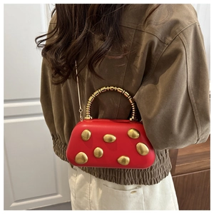 Rote Abendtasche mit goldenen Kiesel-Applikationen, getragen von einem Model