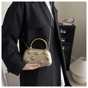 Nahaufnahme der champagnergoldenen Abendtasche mit 3D-Kieselstruktur und Perlengriff