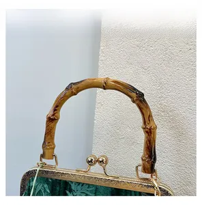 Detail showing deep green velvet texture with bamboo handle and golden metal frame
