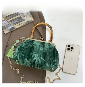 Detail of emerald velvet bag with bamboo handle, leaf texture, and size reference