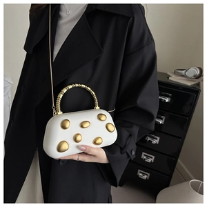 Details der metallischen Pebble-Abendtasche mit Goldakzenten und Spiral-Handgriff