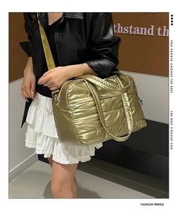 Detail of metallic gold quilted puffer tote bag with green adjustable shoulder strap