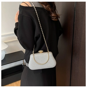 Silver sequin clutch bag with gold chain and jeweled clasp worn by a model in a formal setting