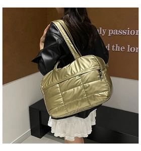 Detail of large metallic gold quilted tote bag with side zipper and wide shoulder strap