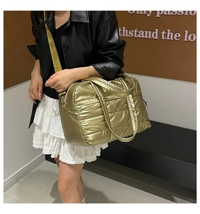 Fashionable gold quilted puffer tote bag shown in a lifestyle street style setting