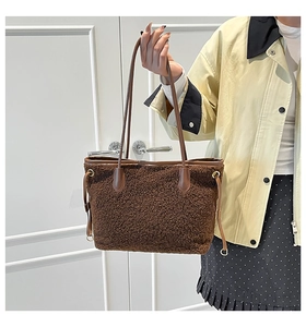 Close-up of dark brown plush tote bag with leather straps and gold hardware details