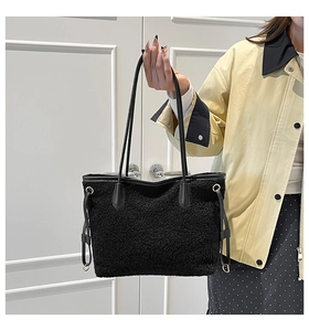 Detail of black plush tote bag with faux fur texture, long strap and drawstring accents