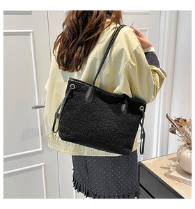 Detail of black faux shearling tote bag with drawstring leather handles and gold metal eyelets