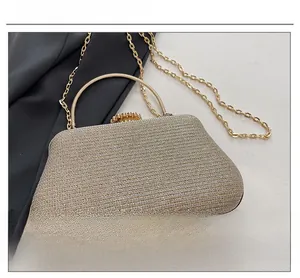 Detailed macro view of the gold glitter fabric and metallic handle on this evening clutch